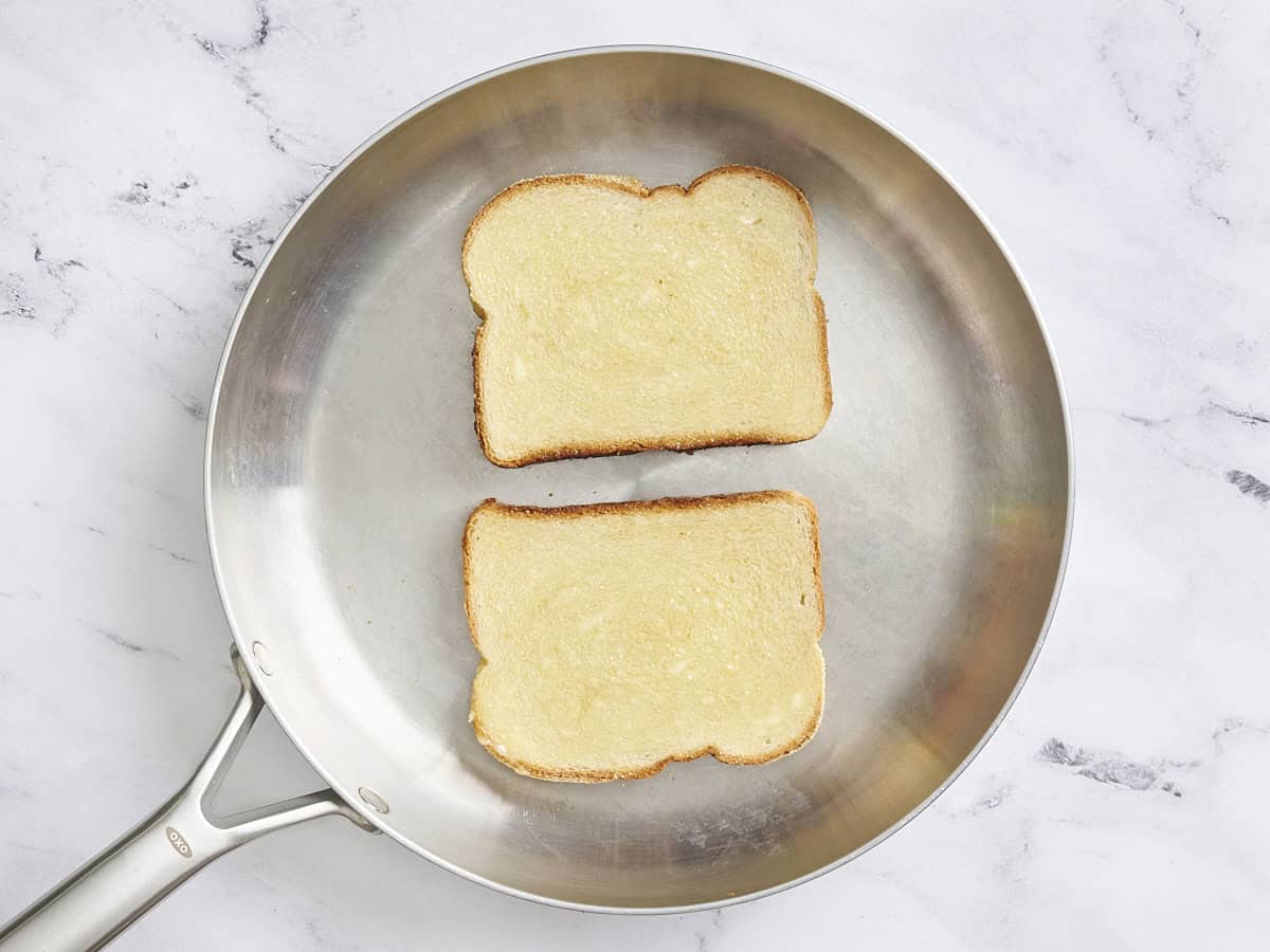 Overhead view of two slices of bread in a skillet.