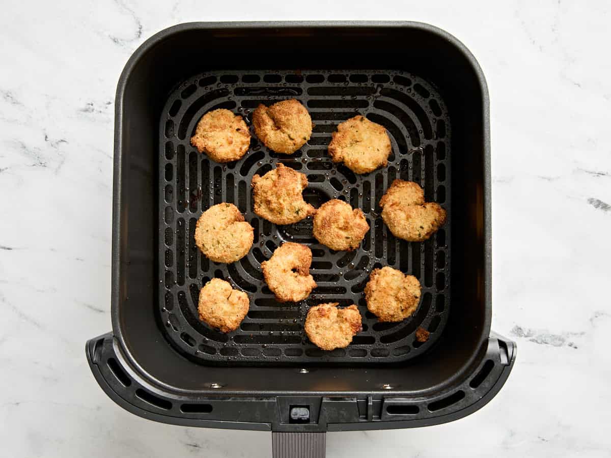 Overhead view of air fried fried shrimp in an air fryer basket.