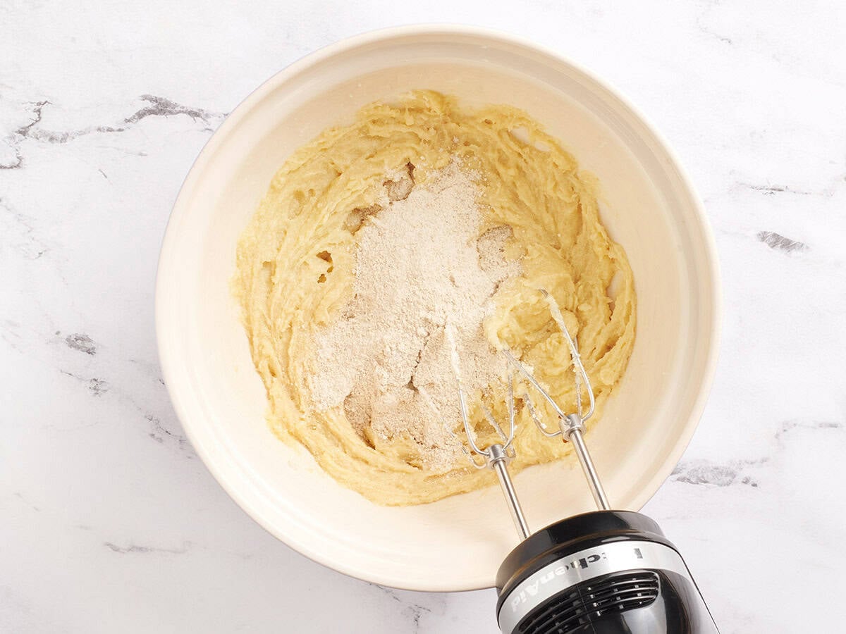 Flour being mixed into cookie dough in a mixing bowl.
