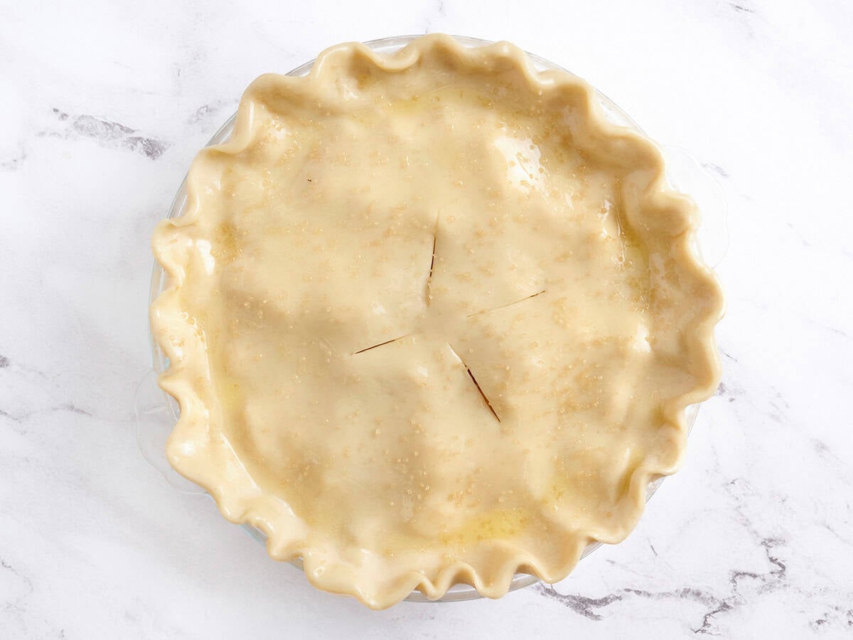 An unbaked peach pie in a pie dish.