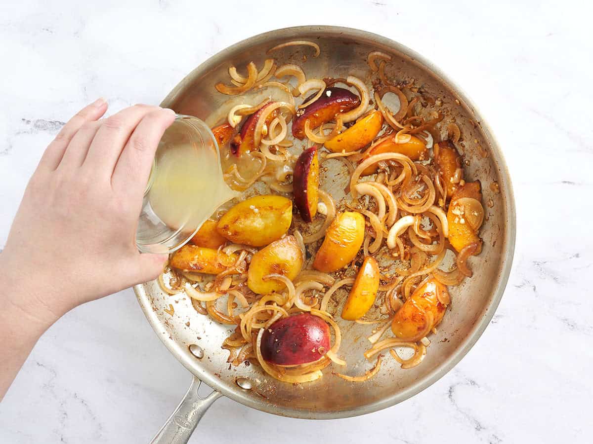 Chicken broth deglazing the skillet with peaches and onions to make a sauce.