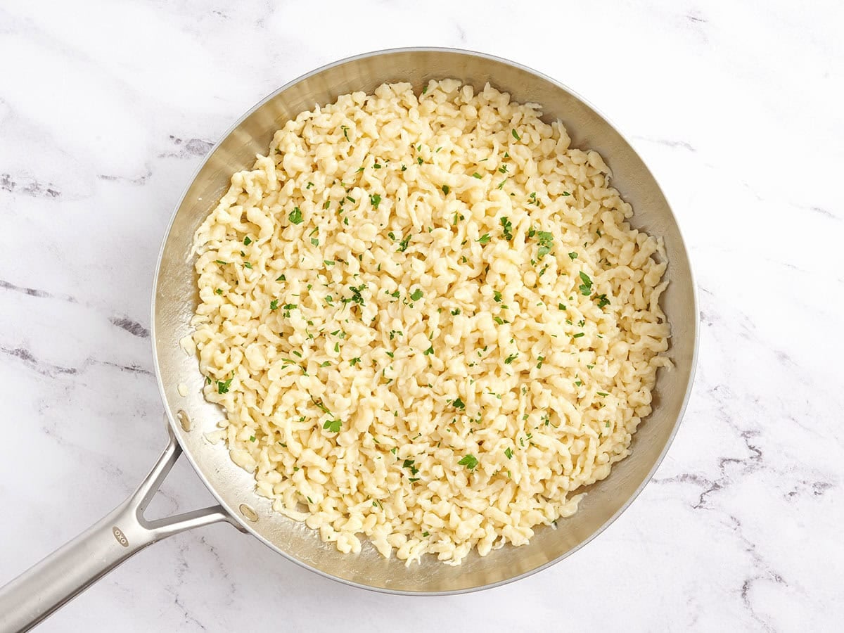 Spaetzle in a skillet with melted butter and parsley.