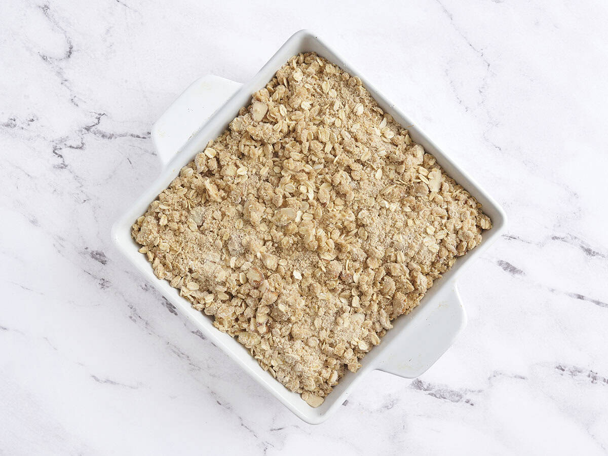 An assembled peach crisp in a baking dish before baking.