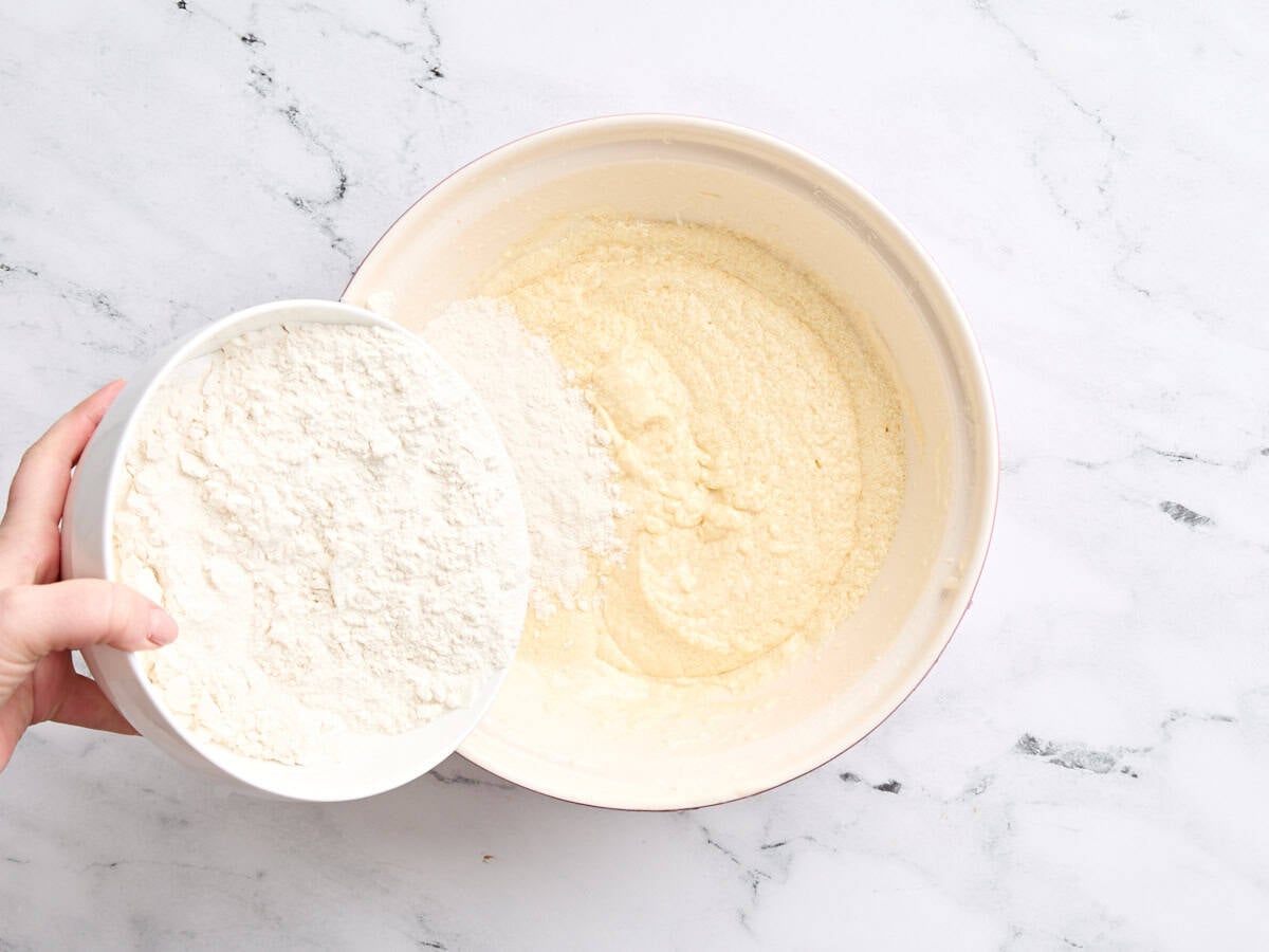 The dry ingredients being combined with the wet ingredients in a bowl to make vanilla cake.