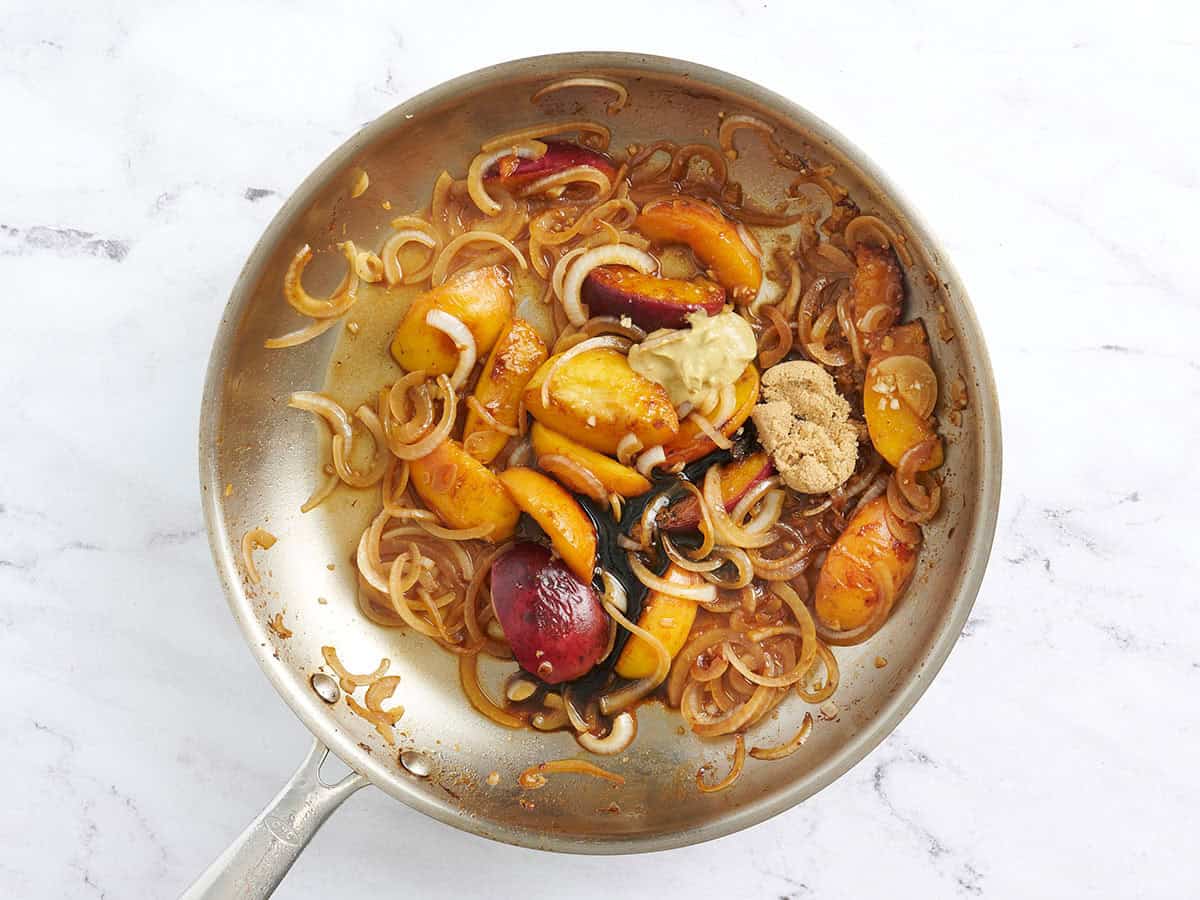 Balsamic vinegar, Dijon, and brown sugar added to a skillet with cooked peach slices and onions.