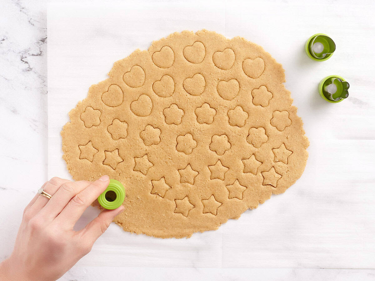 A hand using a mini cookie cutter to cut out cookie dough to make homemade dunkaroos.