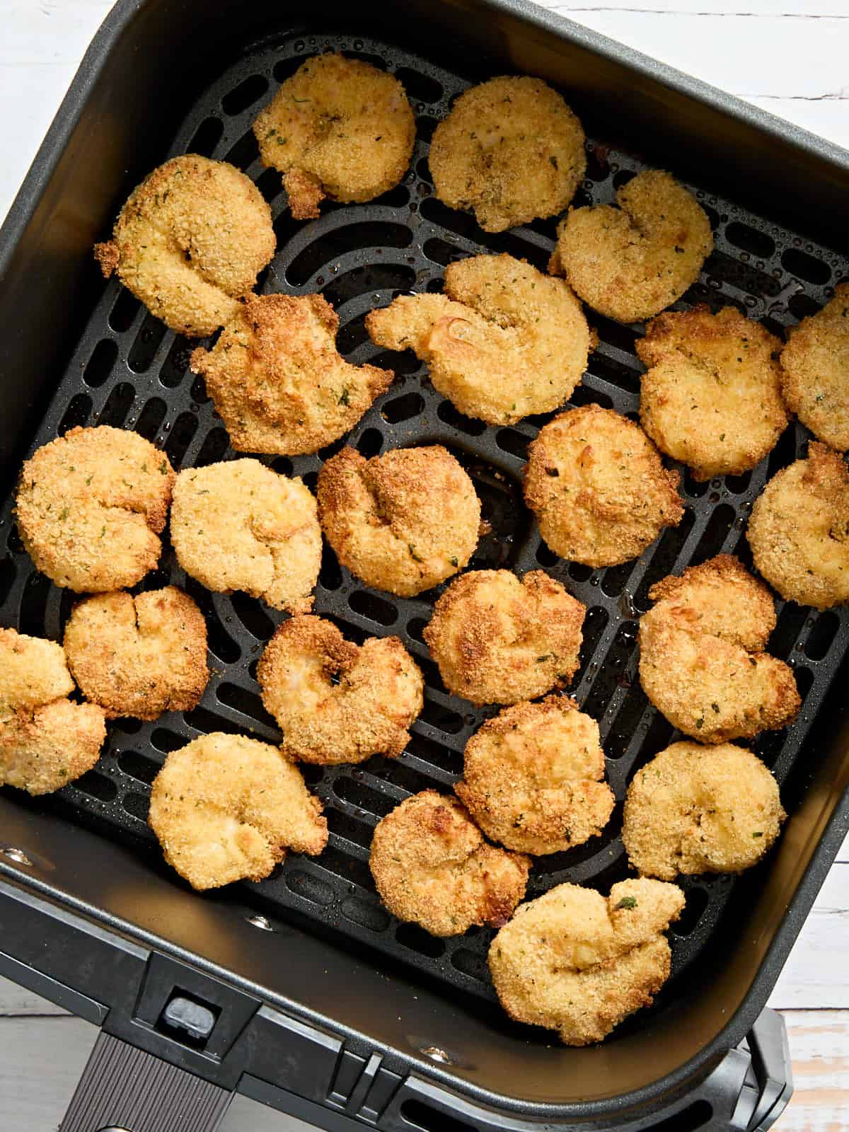 Overhead view of air fryer fried shrimp in an air fryer basket.
