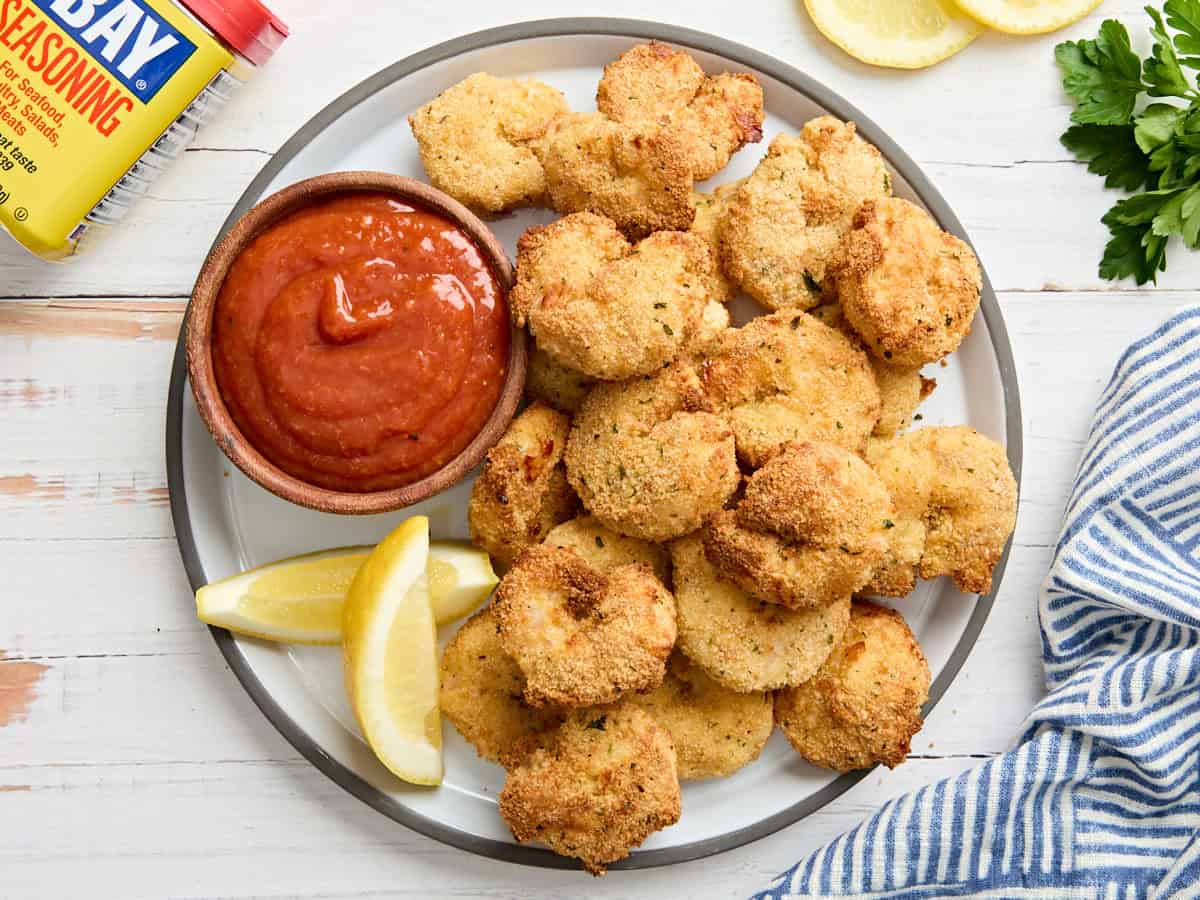 Overhead view of a bowl of cocktail sauce on a plate with fried shrimp.