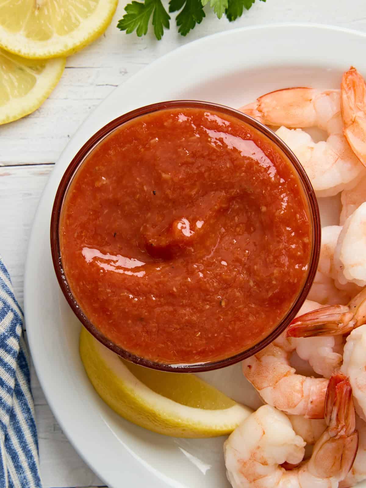 Overhead view of a bowl of cocktail sauce on a plate with shrimp.