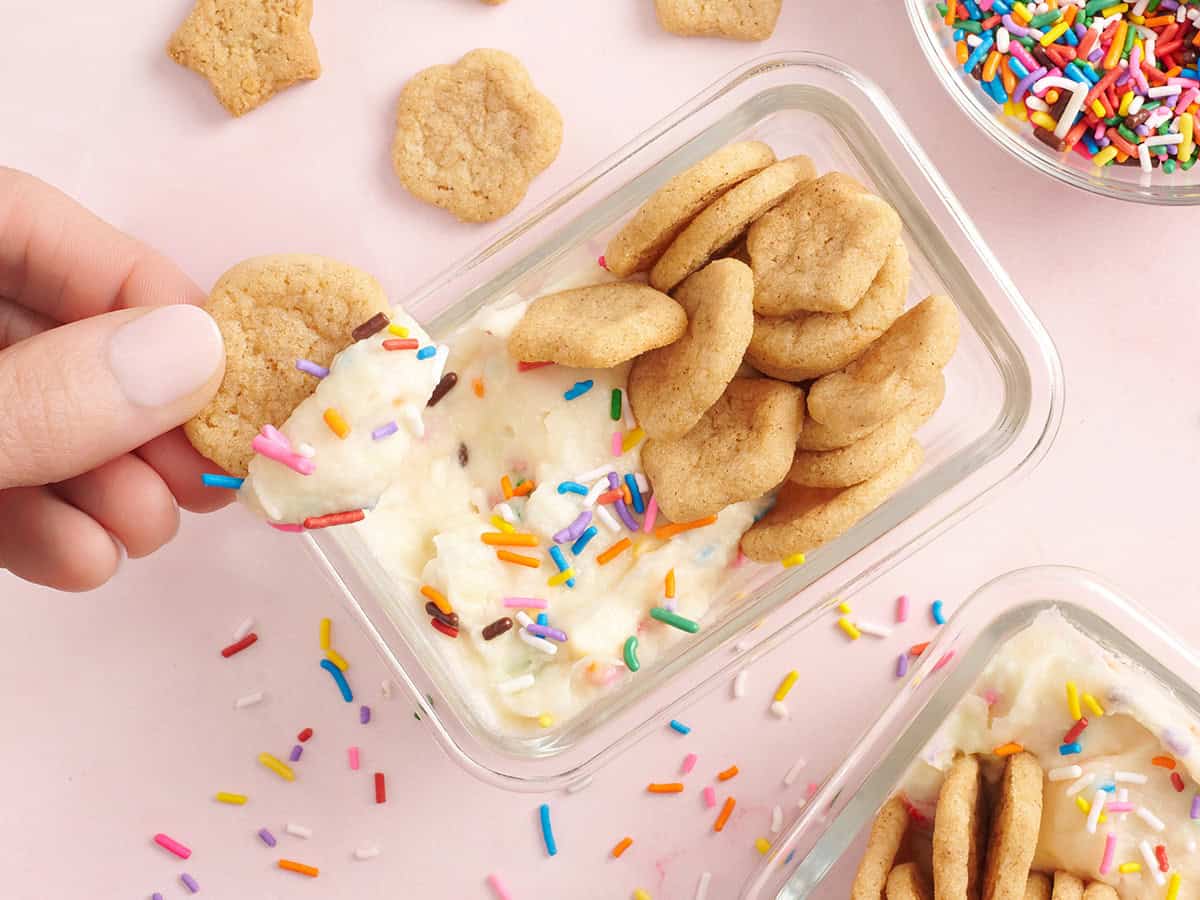 Homemade dunkaroos with a hand holding one dipped in frosting.