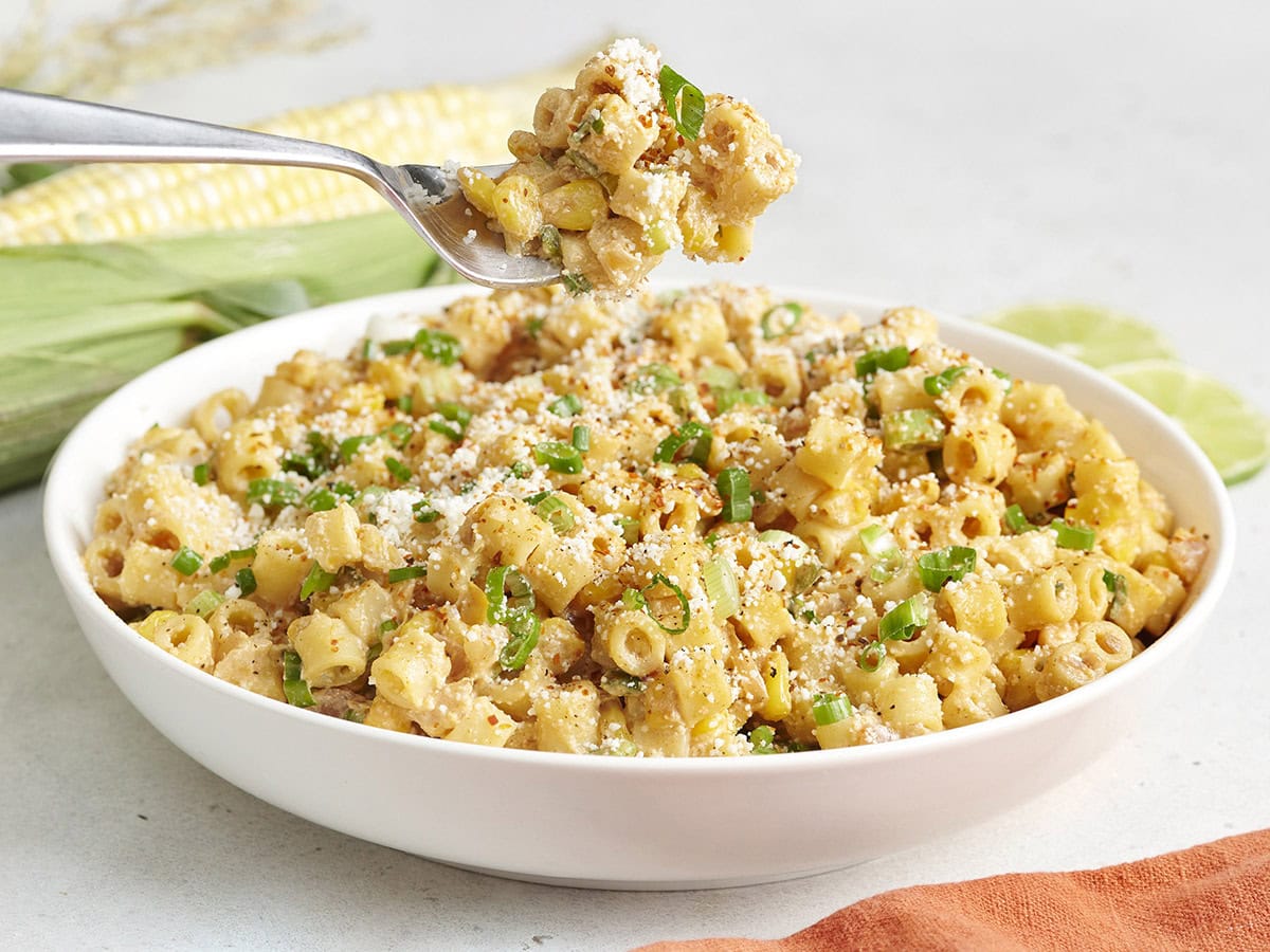 Side view of street corn pasta salad in a bowl with a fork taking some.
