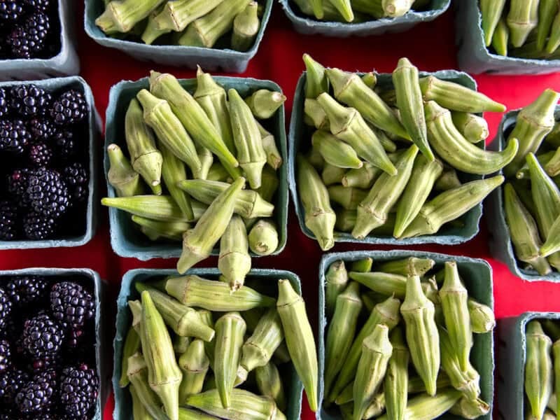 overhead view of okra and blackberries in containers from a farmers market