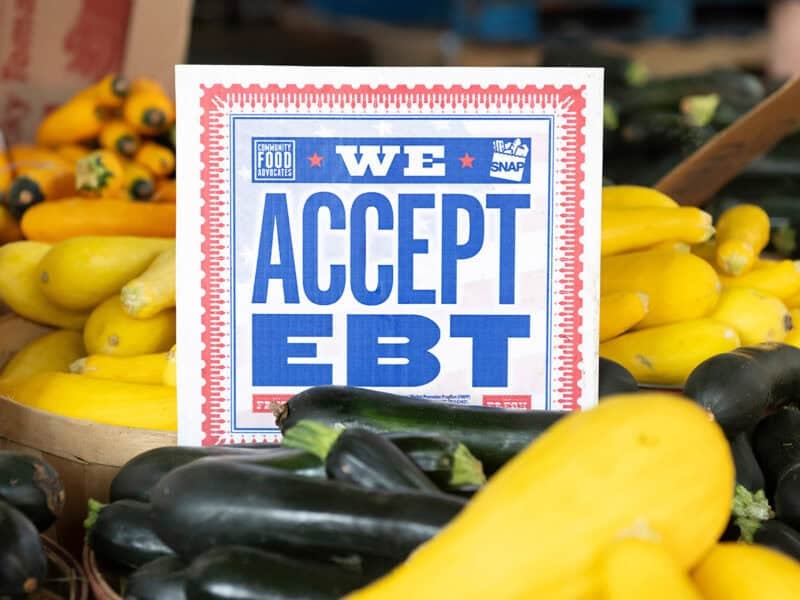 We accept EBT sign amid produce at a farmers market