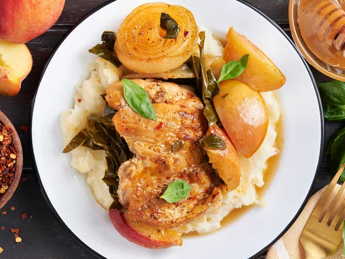 Peach chicken on a plate with mashed potatoes and vegetables.