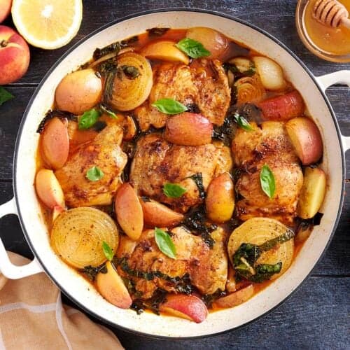 Overhead view of savory braised peach chicken in a skillet.