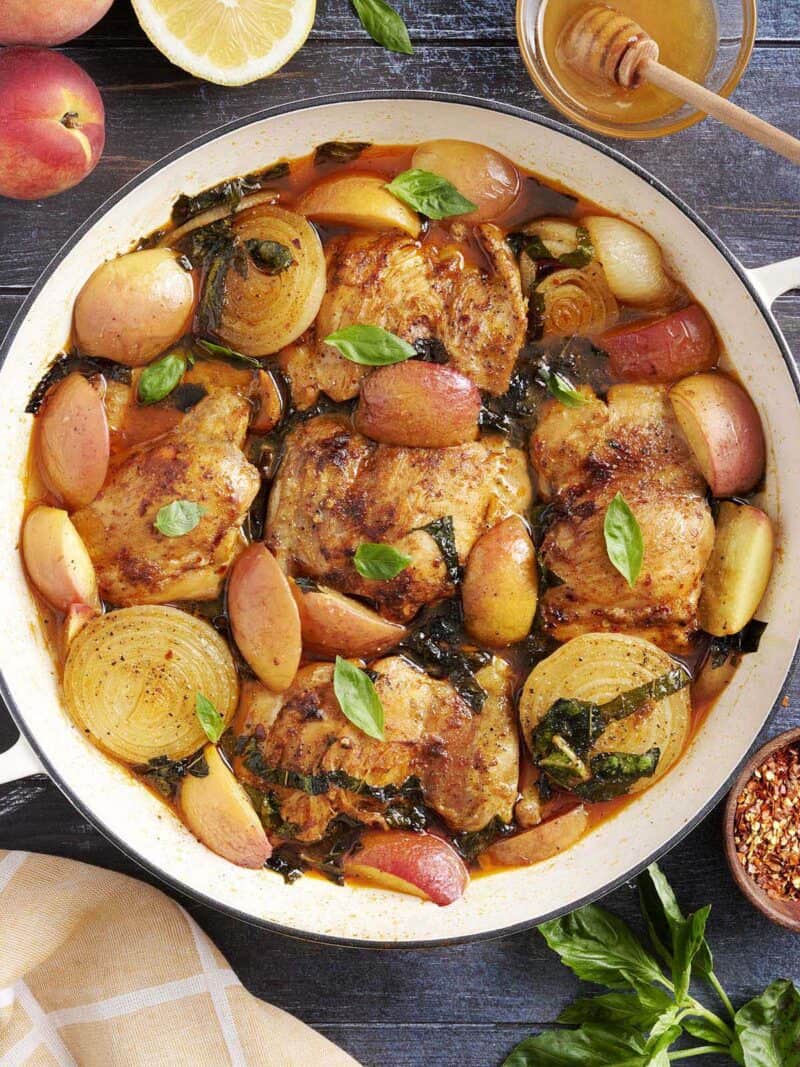 Overhead close up of braised chicken and peaches in a skillet.