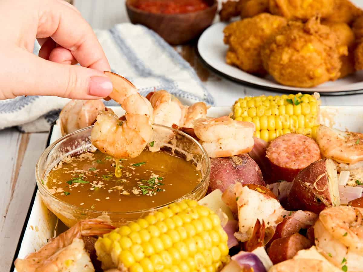 A piece of shrimp being dipped into seasoned butter.