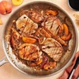 Overhead view of summer peach pork chops in a skillet.