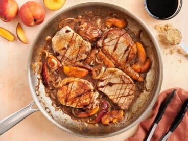 Overhead view of summer peach pork chops in a skillet.