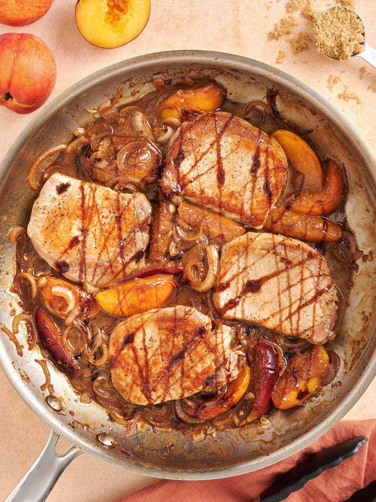 Overhead close up of peach pork chops in a skillet.