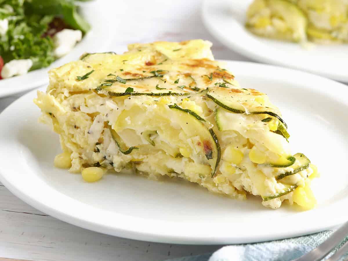 Side view of a slice of sweet corn and zucchini pie on a plate.