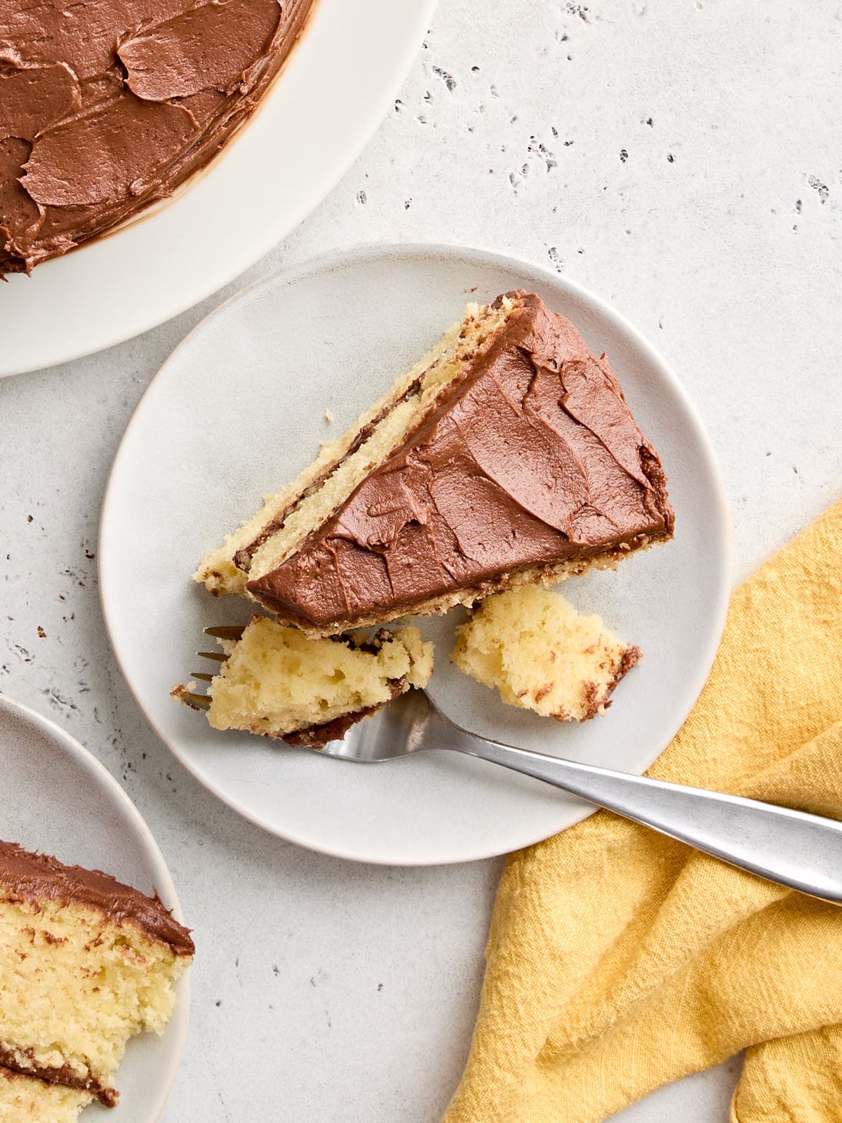 Overhead view of a slice of classic vanilla cake on a plate with a fork.