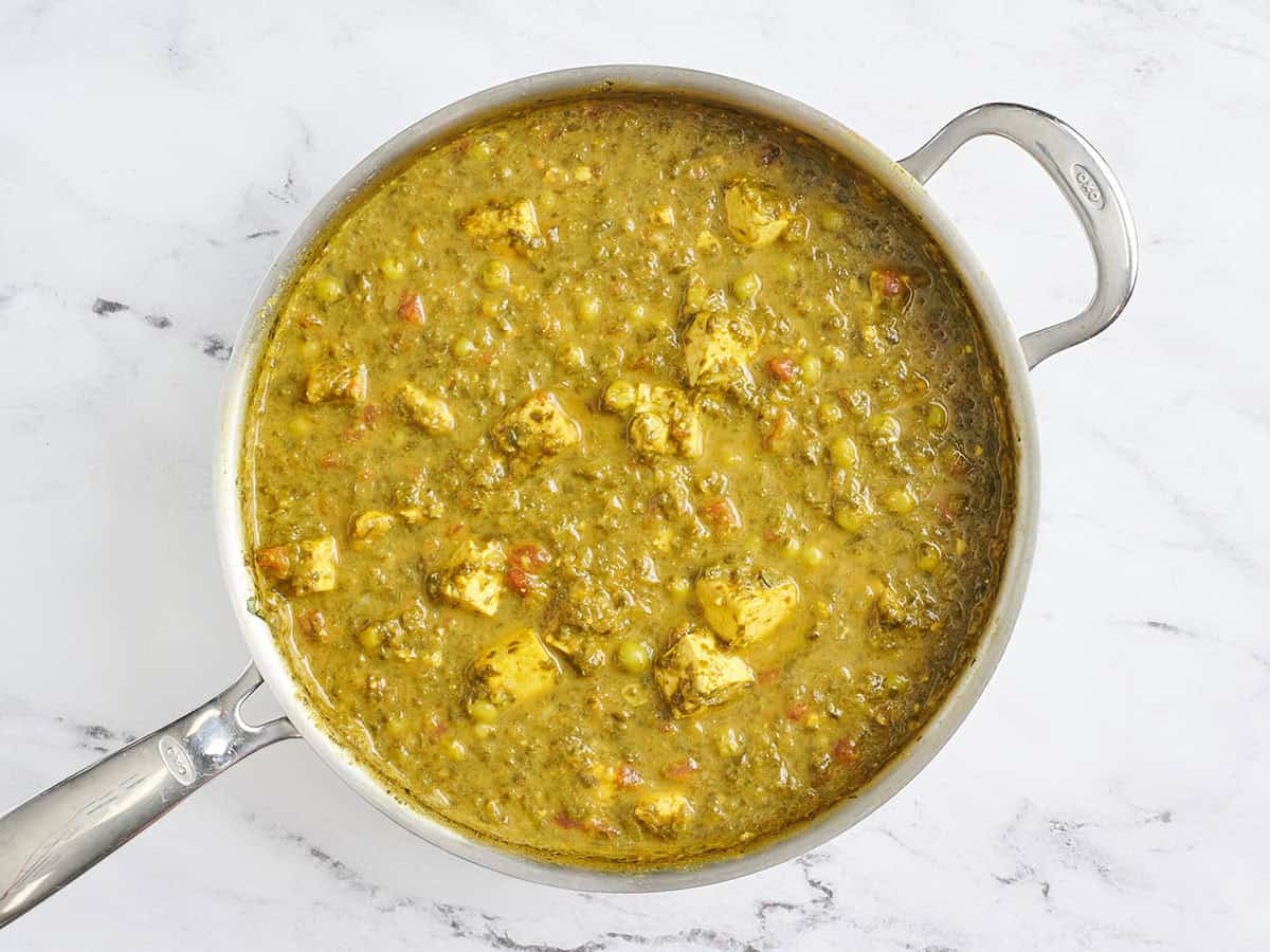 Finished tofu, spinach and green pea curry in a skillet.