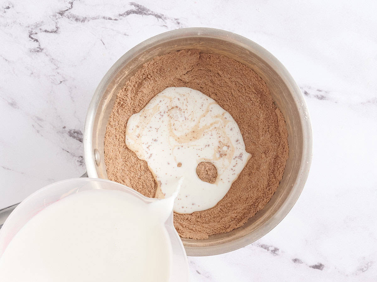 Milk being added to the dry ingredients for homemade chocolate pudding.