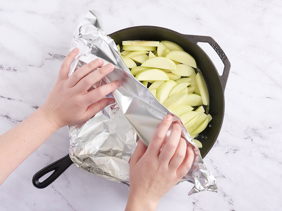 A cast iron skillet being covered with foil.