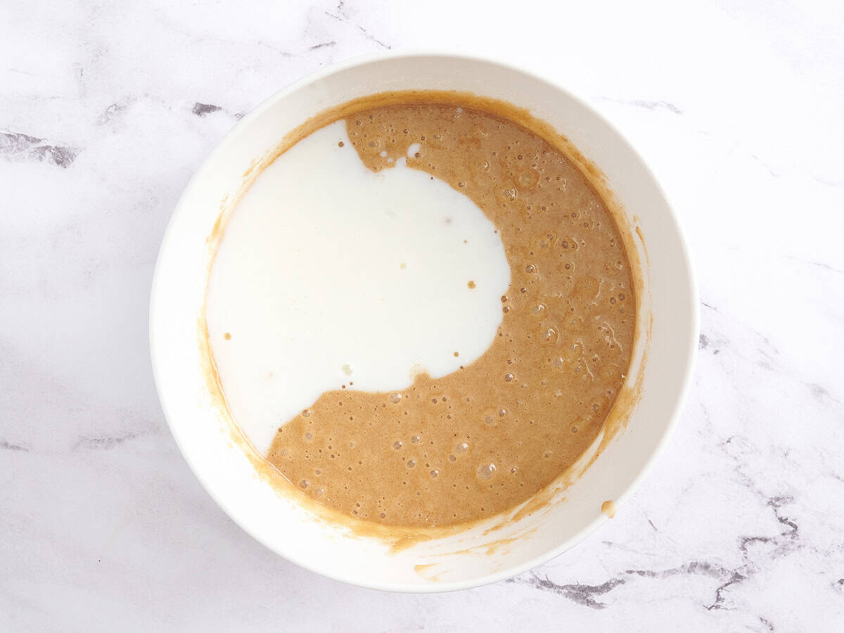Buttermilk added to a bowl of spiced cake batter.