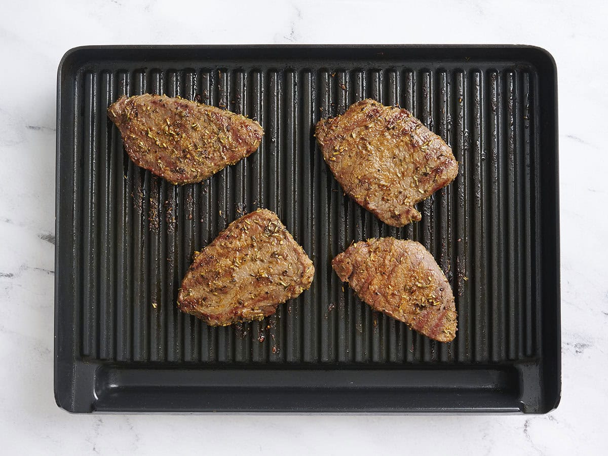 Sirloin tender steaks after being flipped over on a grill.