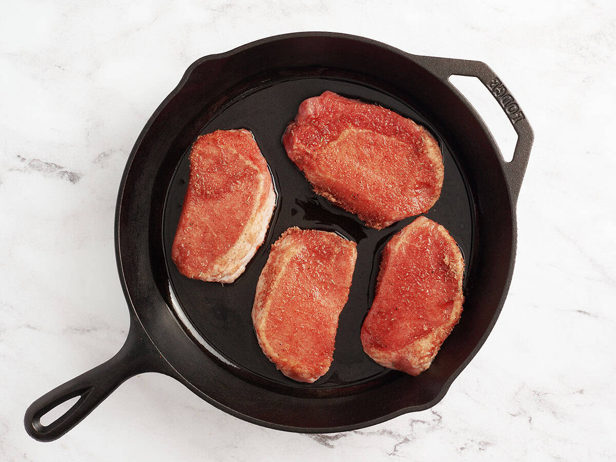 Seasoned pork chops in a skillet.