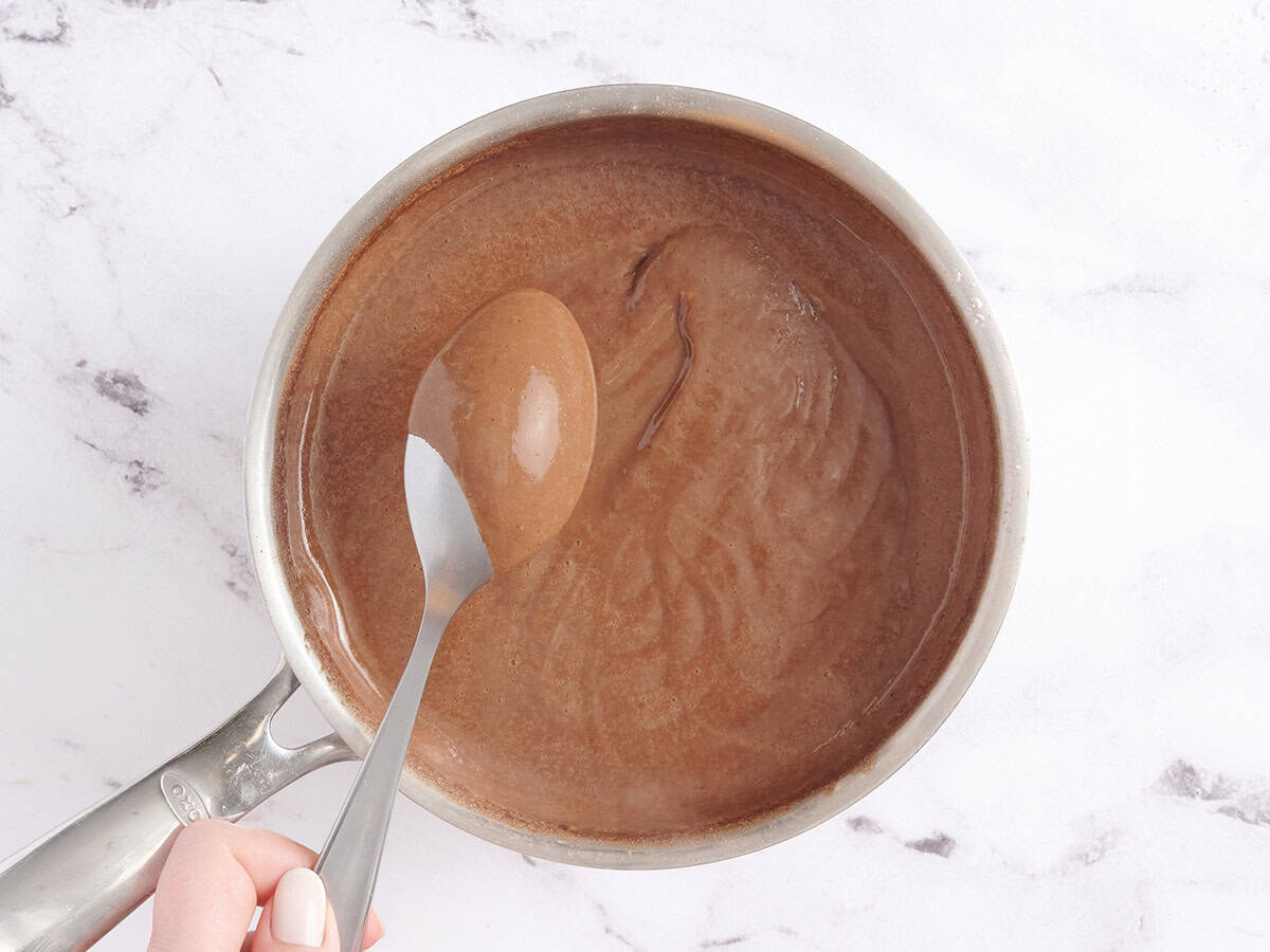 A spoon checking homemade chocolate pudding for thickness.