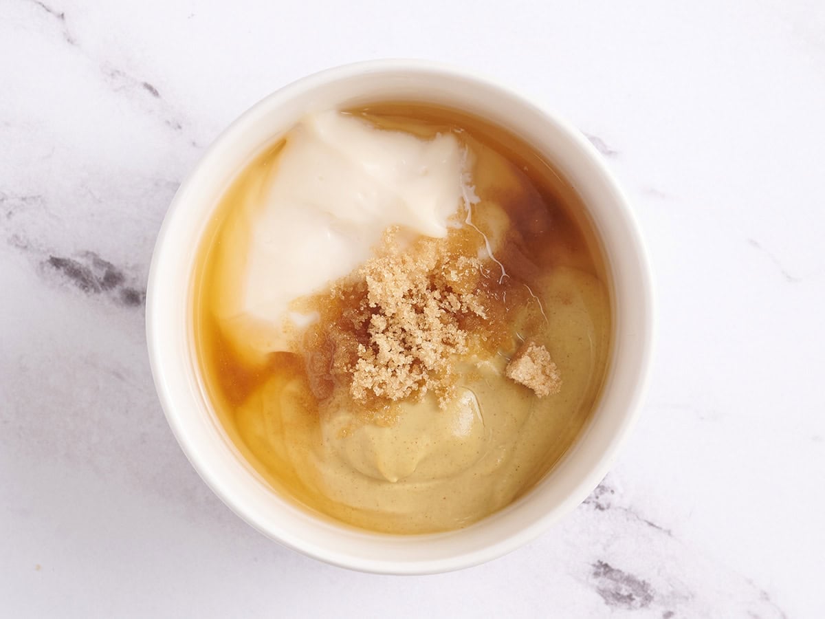 Brown sugar, mayonnaise, mustard, and apple cider vinegar in a bowl to make mustard sauce.