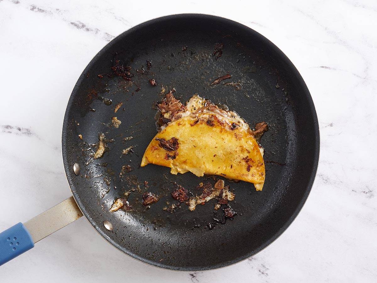 A beef birria taco in a skillet after cooking.