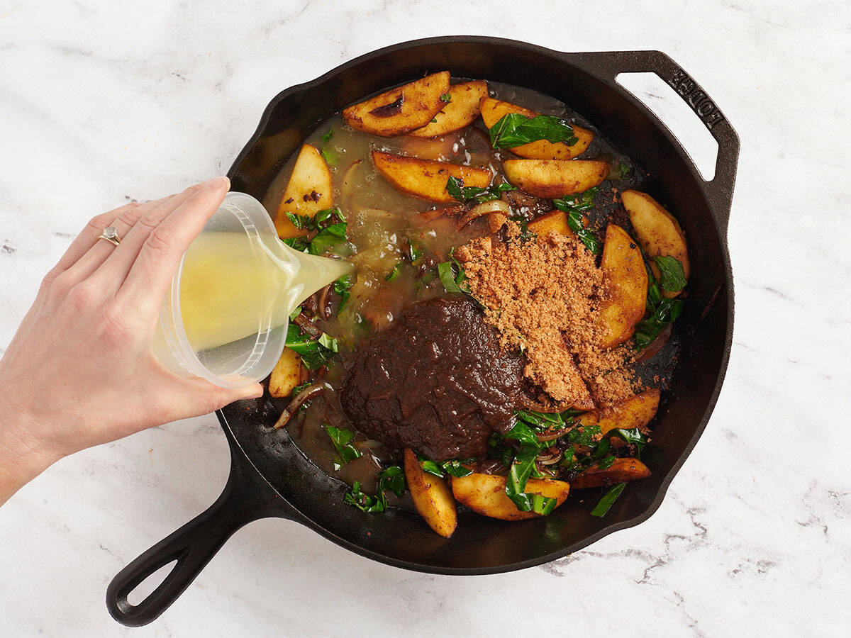 Apple butter, chicken broth and seasonings added to a skillet with onions and collard greens.