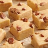 Close up side view of homemade pumpkin spice fudge on parchment paper.