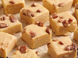 Close up side view of homemade pumpkin spice fudge on parchment paper.