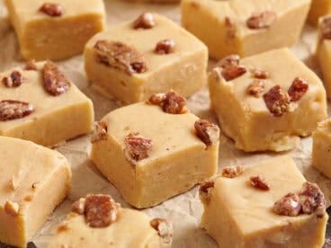 Close up side view of homemade pumpkin spice fudge on parchment paper.