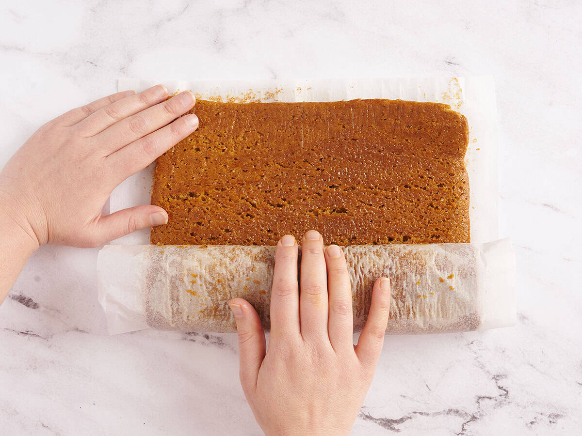 cooled pumpkin roll being unrolled to lay flat