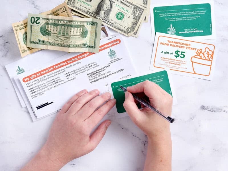 person writing out a donation to help the food bank