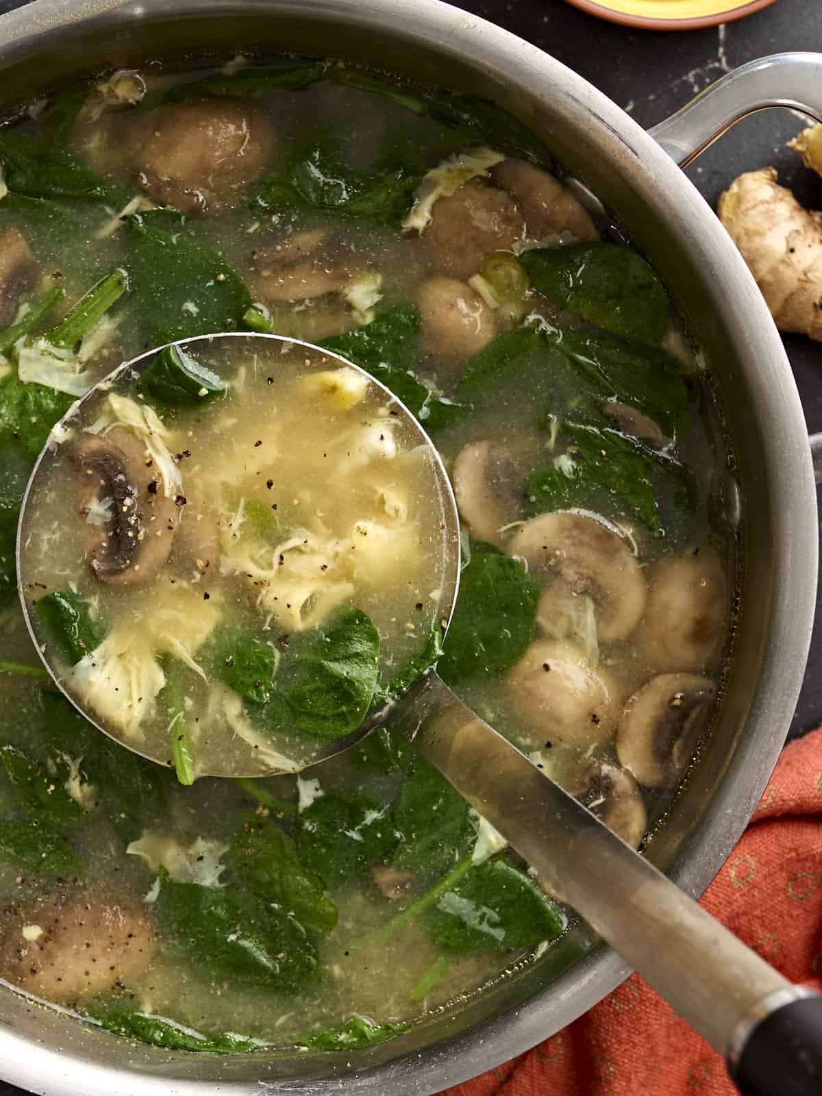 Overhead view of a pot of egg drop soup with a ladle taking some.
