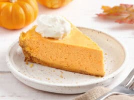 Sideview of a slice of pumpkin cheesecake on a plate.