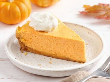 Sideview of a slice of pumpkin cheesecake on a plate.