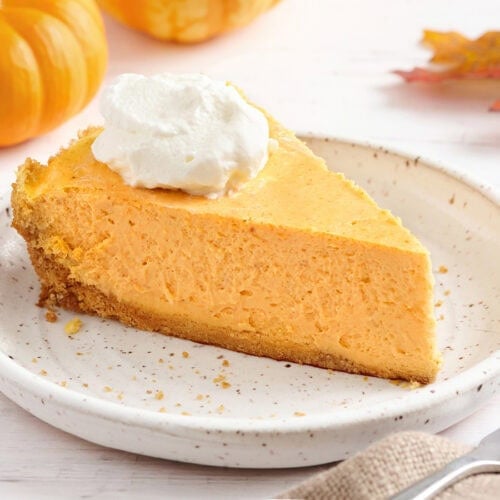 Sideview of a slice of pumpkin cheesecake on a plate.