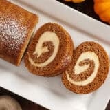 Overhead view of a homemade pumpkin roll with two slices.