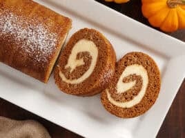 Overhead view of a homemade pumpkin roll with two slices.