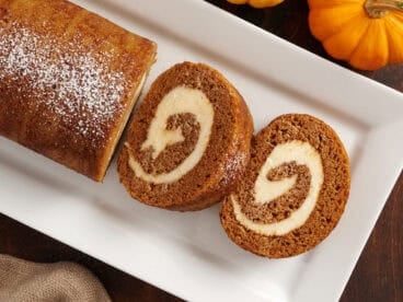 Overhead view of a homemade pumpkin roll with two slices.