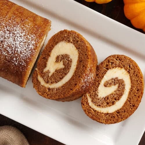 Overhead view of a homemade pumpkin roll with two slices.