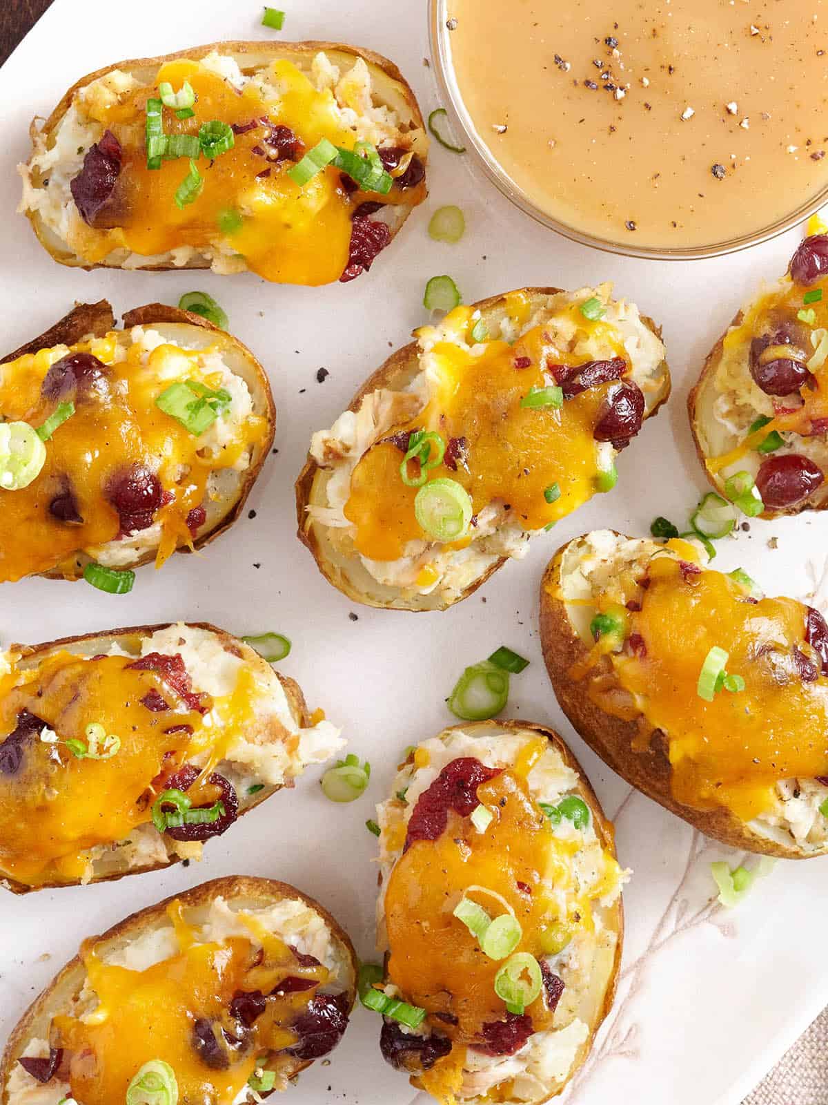 Overhead view of thanksgiving potato skins on a plate with a small bowl of gravy.